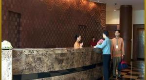 tre persone in piedi a un bancone in una hall di Sri U-Thong Grand Hotel a Suphanburi