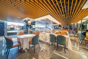 a restaurant with tables and chairs and a bar at Urumqi Bayinhe Hotel in Ürümqi