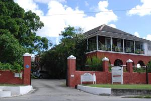 a red brick house with a sign in front of it at Charming Old World Apartment in Bridgetown