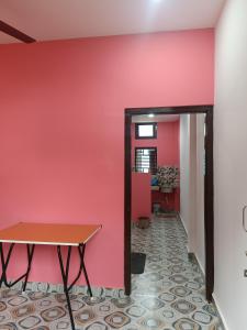 a room with a red wall and a table at Destiny Lodge & Homestay in Nāzirā