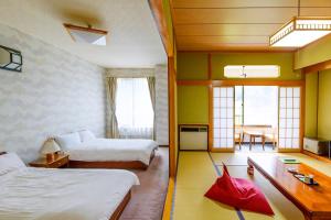 a hotel room with two beds and a dining room at IkazawaYumotokan in Minami Uonuma