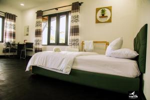 a bedroom with a large bed with white sheets and pillows at Tin Tin Lodge in Ella