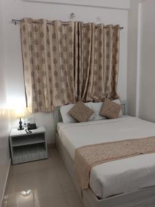 a bedroom with two beds and a window with curtains at Sai Inn Mysore in Mysore