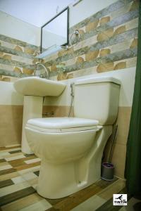 a white toilet in a bathroom with a brick wall at Tin Tin Lodge in Ella