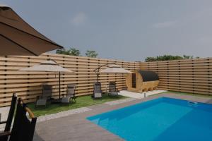 Ein Swimmingpool mit Liegestühlen und Sonnenschirmen neben einem Zaun in der Unterkunft HiTOSE in Takashima