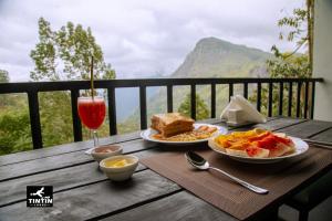 a table with two plates of food and a glass of wine at Tin Tin Lodge in Ella