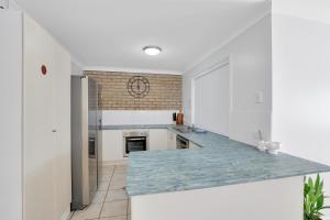 a kitchen with white cabinets and a blue counter top at Barefoot Haven in Amity Point +3 photos