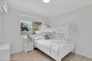 a white bunk bed in a white room with a window at Barefoot Haven in Amity Point