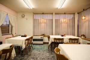 a room with tables and chairs with white table cloths at 旅館おぎた Ryokan Ogita - near Shiraoi Station in Shiraoi