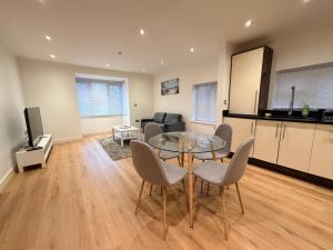 a living room with a glass table and chairs at Sleek Modern 2BDR Flat in Charming Pinner in Northwood