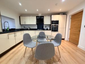 a kitchen with a glass table and four chairs at Sleek Modern 2BDR Flat in Charming Pinner in Northwood