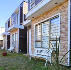 a white bench sitting outside of a house at Cabañas Perlas del Sur in Valdivia