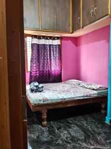 a small bed in a pink room with a window at M R ViLLA HAMPI magic rock villa in Hampi