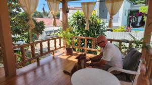 a man sitting in a chair with a dog on a porch at Beach Path in Haad Chao Phao