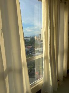 a window with white curtains and a view of a city at 2 Bedroom Condominium in Cagayan de Oro