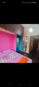 a bedroom with a pink bed and a room with cabinets at M R ViLLA HAMPI magic rock villa in Hampi