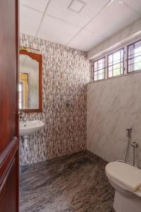a bathroom with a toilet and a sink and a mirror at Orma in Cochin