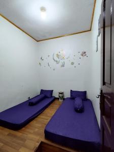 2 letti in una camera con cuscini viola di Villa berastagi murah bukit asri a Medan