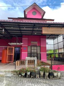 un edificio rosa con piante in vaso di fronte ad esso di Villa berastagi murah bukit asri a Medan