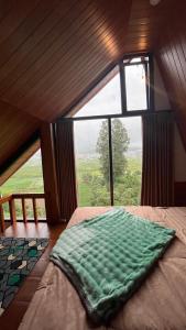 a bed in a room with a large window at Padangsari Cabin House in Diyeng