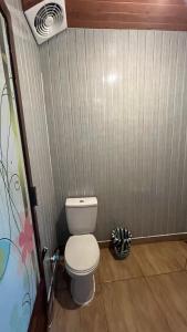 a bathroom with a white toilet in a room at Padangsari Cabin House in Diyeng
