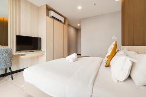 una camera da letto con un letto bianco e una tv di Societe Suites By iHost Global a Kuala Lumpur