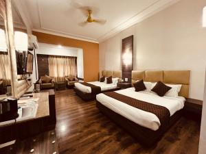 a hotel room with two beds and a television at Hotel Asia Vaishnodevi Katra in Katra