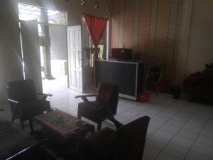 a living room with chairs and a large tv at Capital O 92080 Green Home Stay in Ciamis