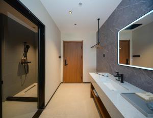 een badkamer met een wastafel en een spiegel bij Leaf Hotel in Yantaiqian