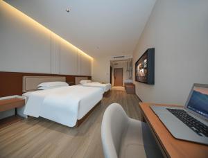 een slaapkamer met 2 bedden en een laptop op een bureau bij Leaf Hotel in Yantaiqian