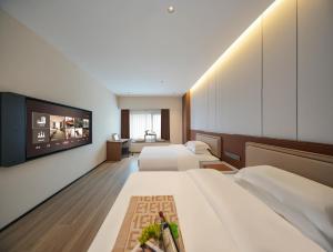 een hotelkamer met twee bedden en een flatscreen-tv bij Leaf Hotel in Yantaiqian