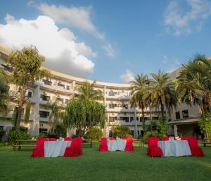 Eine Gruppe von Tischen mit roten Stühlen vor einem Gebäude in der Unterkunft Siddhartha Hotel Narayangarh in Bharatpur