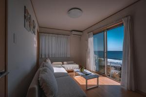 a living room with a couch and a large window at 波音ハウス湯河原ー心地よい波Waveの音に包まれる癒しの別荘BBQ可 in Yugawara