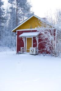 a red barn with snow on the ground in front of it at Pehtoorin Kammarit in Iltasmäki