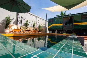 a pool with chairs and an umbrella next to a train at Baan Rot Fai Krabi Platform 2 in Ao Nam Mao