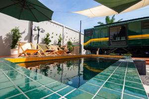a pool with chairs and an umbrella next to a train at Baan Rot Fai Krabi Platform 2 in Ao Nam Mao