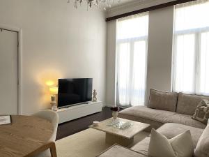 a living room with a couch and a flat screen tv at Beautiful condominium with jacuzzi in Brussels