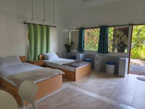 a room with two beds and a chair and windows at Niyang Siam House in Nai Yang Beach