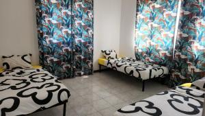 two twin beds in a room with floral curtains at Meeting Point Hostels-Praia Beachwalk-NO CASH ACCEPTED-Also in Fogo & Tarrafal in Praia