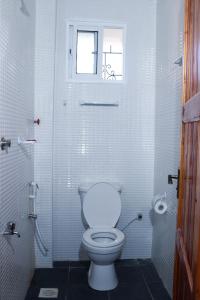 a white bathroom with a toilet and a window at Raels home in Mombasa