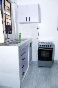 a white kitchen with a stove and a sink at Raels home in Mombasa