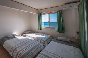 een slaapkamer met 2 bedden en een raam met uitzicht op de oceaan bij 波音ハウス in Yugawara