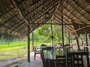a group of tables and chairs under a straw roof at Wild Wadi Wilpattu - Villas with private Plunge Pools in Ilavankulam