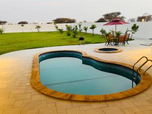 a swimming pool with a table and an umbrella at Rimal Chalet in Barka