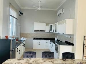 a white kitchen with white cabinets and blue chairs at Rimal Chalet in Barka