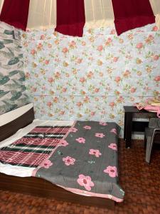a bed with a blanket with pink flowers on it at SS Aadhya Retreat in Payikāpuram