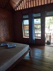 a bedroom with a bed and a large window at Togean Pulotiga Resort in Popolii