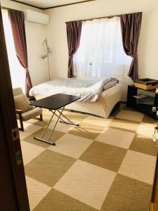 een slaapkamer met een bed en een tafel voor een raam bij れのん in Okazaki