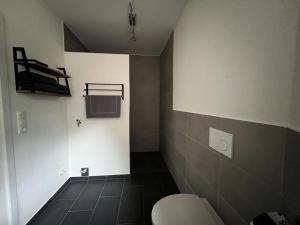a bathroom with a white toilet and a black tile floor at Gemütliche Ferienwohnung in Hüttblek in Hüttblek