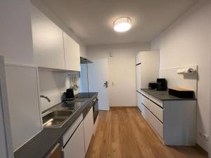 a kitchen with white cabinets and a stainless steel sink at Gemütliche Ferienwohnung in Hüttblek in Hüttblek